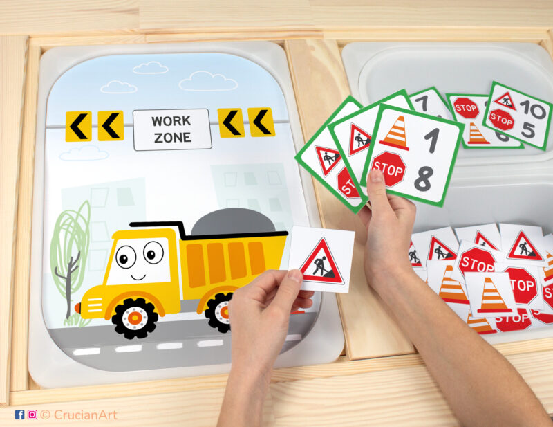 Toddler sensory play: Funny Dump Truck worksheet for an educational activity inserted into IKEA Flisat table, with road signs counters placed in the Trofast box.