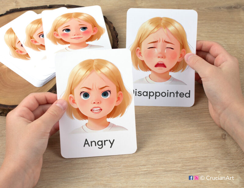 Preschooler hands holding flashcards with watercolor images of Angry and Disappointed girl faces. Emotions and Feelings flash cards for girls with fair hair and skin.