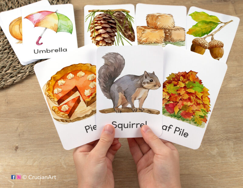Flashcards featuring watercolor illustrations of Squirrel, Leaf Pile, and Pie in toddler's hands. Cozy Fall seasonal vocabulary visuals.