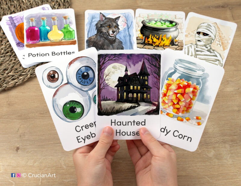 Flashcards featuring watercolor illustrations of Haunted House, Candy Corn, and Creepy Eyeballs in toddler hands. Printable set of Halloween Holiday themed visual cards.