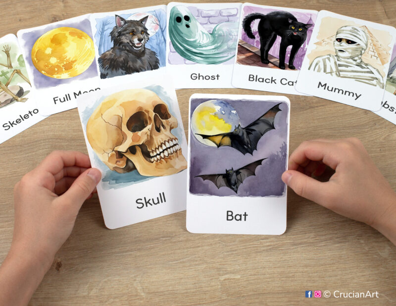 Halloween Season watercolor illustrations of Bats and Skull flashcards in kindergartener hands. Fall Holiday printable visual cards.