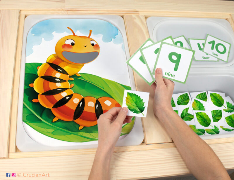 Toddler sensory bins play: Hungry Caterpillar worksheet for an educational activity. DIY template inserted into IKEA Flisat table, with green leaves counters placed in the Trofast box.