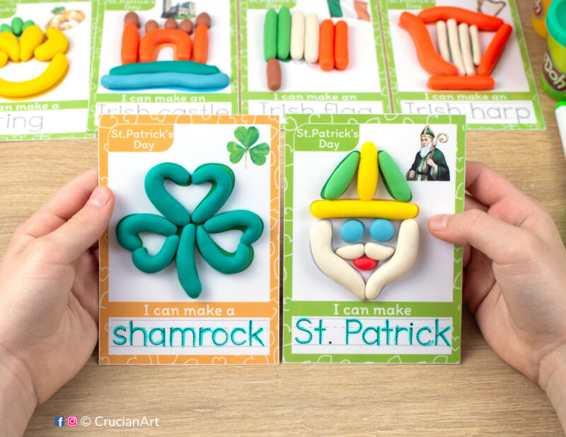 Saint Patrick Day hands-on playdough activities for preschool and toddler curriculum. Preschooler holds two play doh mats with images of St. Patrick and Shamrock.