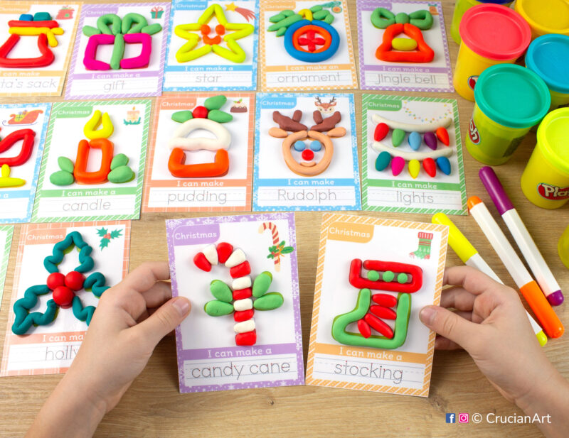 Christmas Holiday season hands-on playdough activities for preschool and toddler curriculum. Preschooler holds two play doh mats with images of Stockings and a Candy Cane.