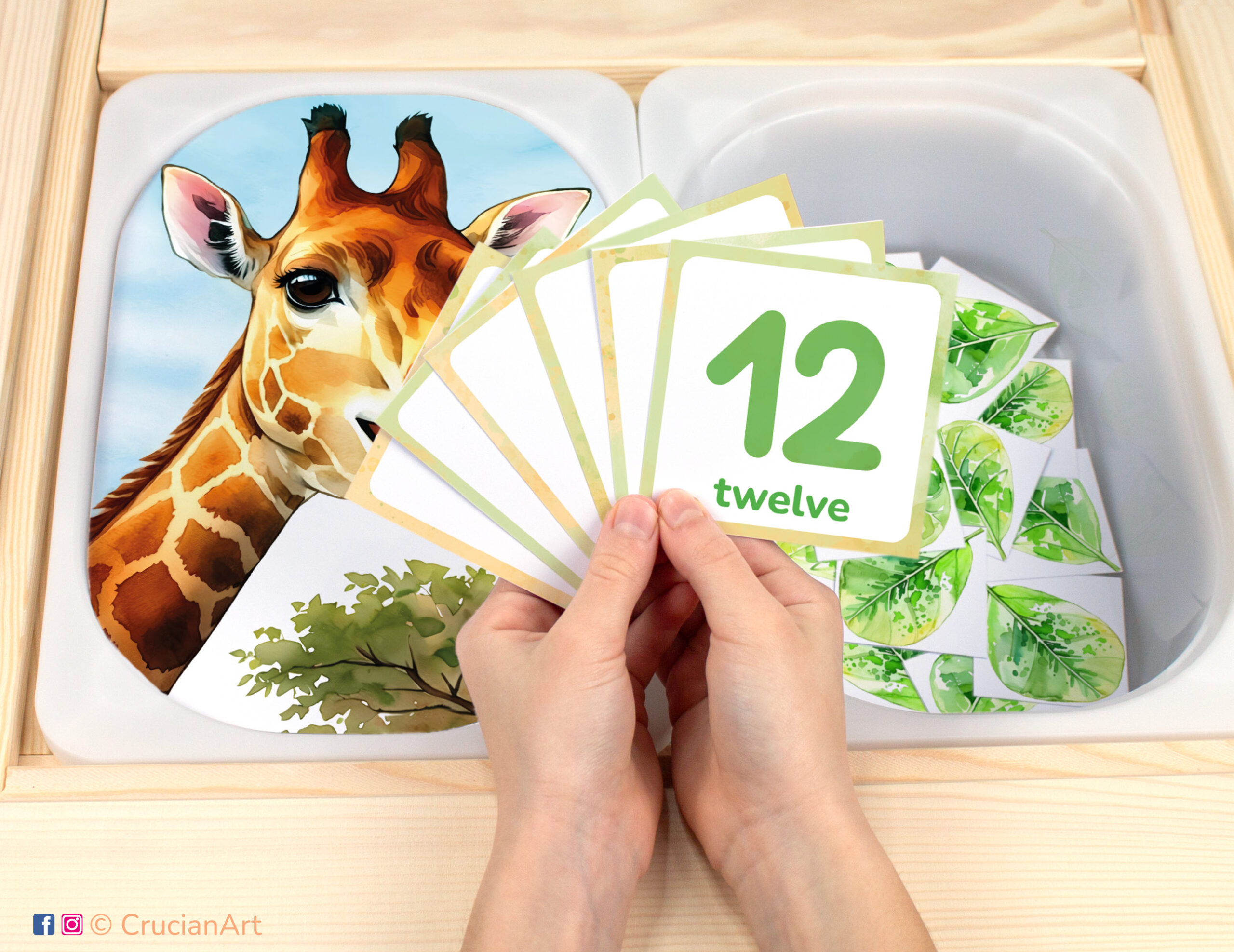 Feed the giraffe leaves pretend play setup. Sensory table insert and kids' hands holding task cards displaying numerals from 1 to 12.