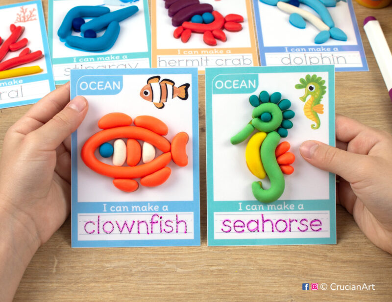 Sea Animals hands-on play-doh activities for preschool and toddler curriculum. Preschooler holds two playdough mats with images of two ocean animals - a clownfish and a seahorse.