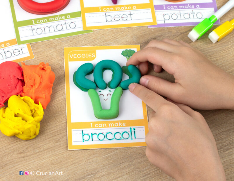 A preschooler is playing with play-doh, molding a broccoli. Fruits and veggies playdough mats for toddlers fine motor skill development.