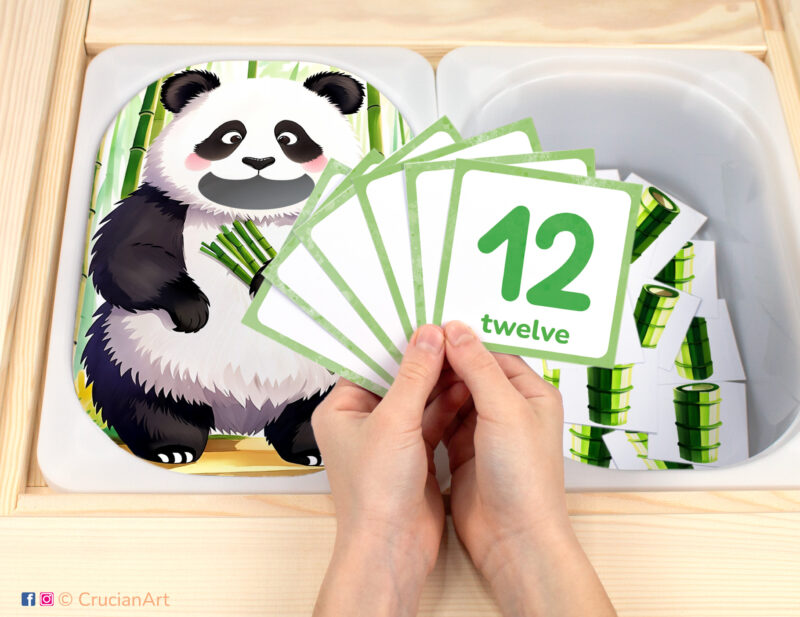 Feed the panda bamboo pretend play setup. Sensory table insert and kids hands holding task cards displaying numerals from 1 to 12. Printable activity for wild animals curriculum.