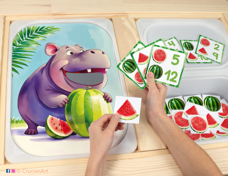 Toddler sensory play: hungry hippo worksheet for an educational counting activity inserted into IKEA Flisat table and counters with watermelon slices placed in the Trofast bin.