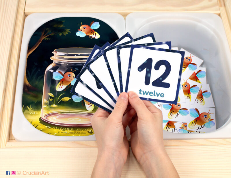 Catching fireflies in a jar pretend play setup. Sensory table insert and kids hands holding task cards displaying numerals from 1 to 12. Printable activity for summer insects curriculum.