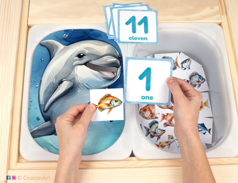 Feed the Dolphin fish counting game for toddlers: ocean animals theme worksheet for an educational activity. DIY template inserted into ikea flisat table, with counters placed in the trofast bin.